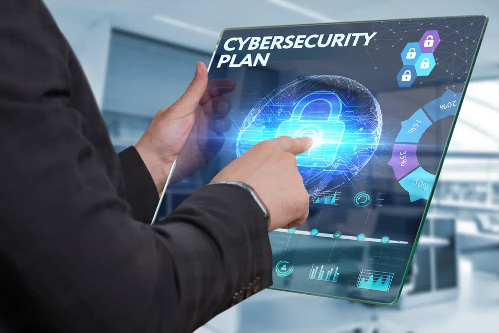 A person touching a lock on a screen with the words 'cybersecurity plan'
