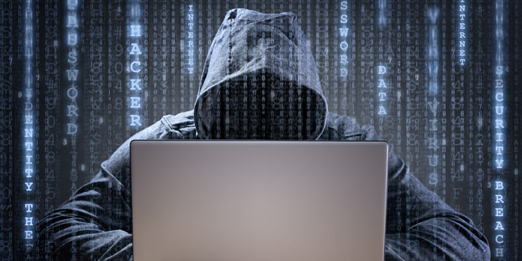 A person in a hoodie working on a laptop
