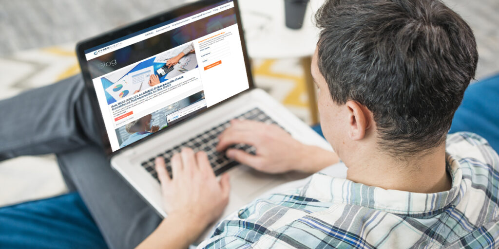 A person working on a laptop with CyberSheath's website pulled up