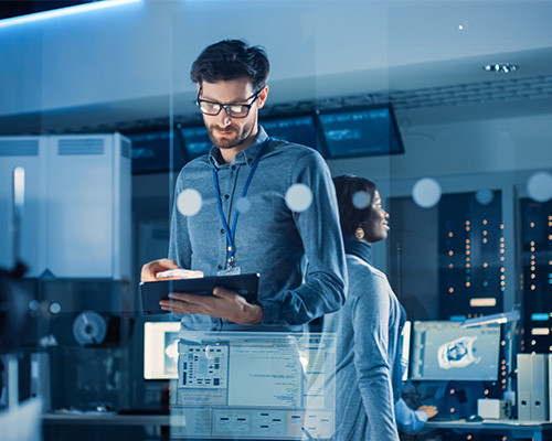 A man looking at a tablet in a room of computers