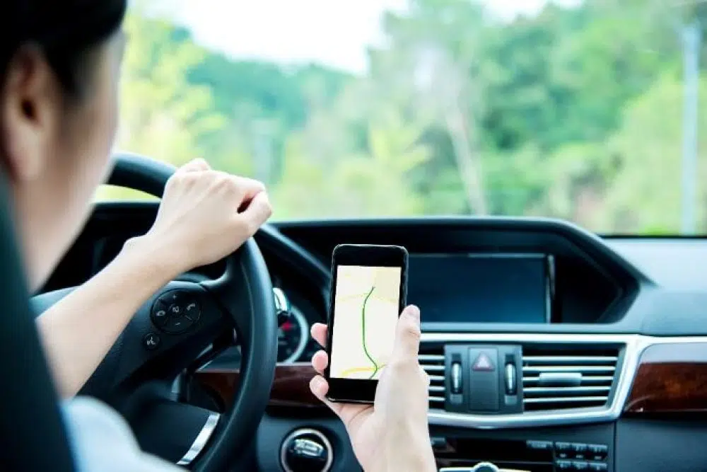 A person driving a car using navigation on a cell phone
