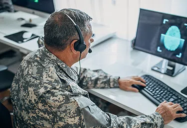Military personnel working on a desktop computer