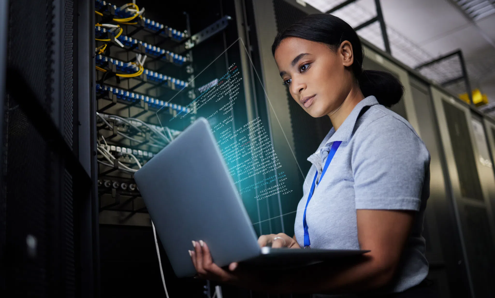 Woman with laptop next to server.